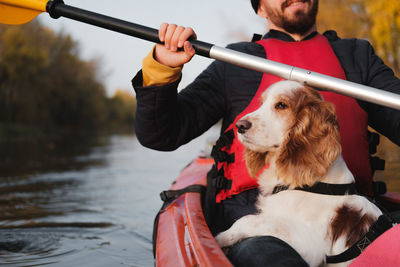 Midsection of man sitting in kayak with dog in sea