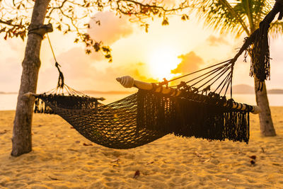 Close-up of swing on beach against sky during sunset