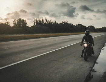 Rear view of man riding bicycle on road