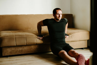 Man exercising against sofa at home