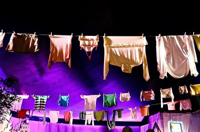 Low angle view of illuminated lanterns hanging against black background