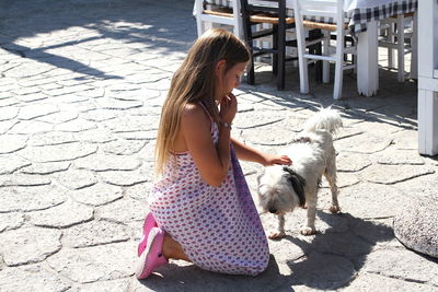 Side view of girl with dog sitting outdoors
