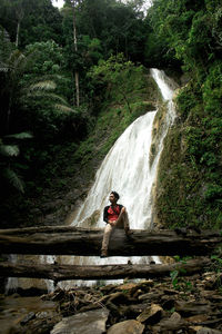 Man standing by waterfall in forest
