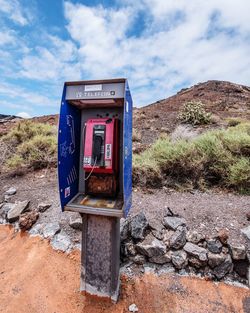 Telephone booth on field against cloudy sky