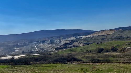 Scenic view of landscape and mountains against blue sky