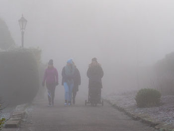 Rear view of people walking on footpath during winter