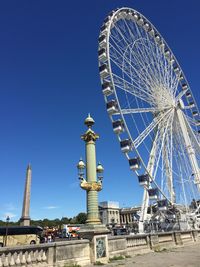 Low angle view of ferris wheel against clear blue sky