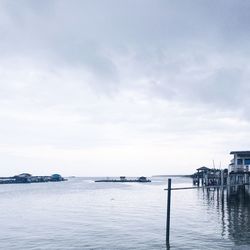 Stilt houses over sea against sky