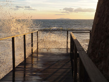 Pier over sea against sky during sunset