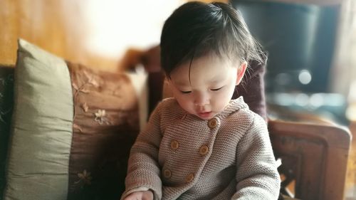 Cute toddler sitting on sofa at home