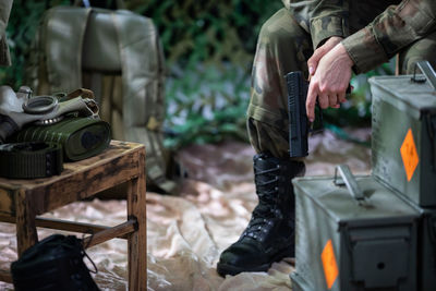 The lady soldier sits on a chair and holds a gun in her hands.