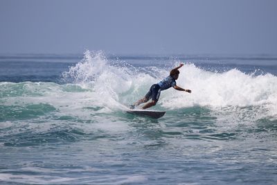 Man surfing in sea against sky