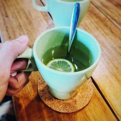 Close-up of hand holding coffee cup on table