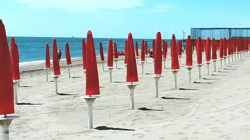 Row of deck chairs on beach against sky