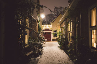 Frozen footpath amidst buildings against sky