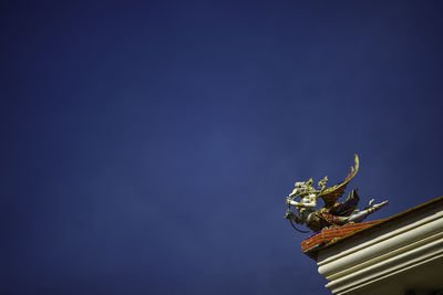 Low angle view of statue against building against blue sky