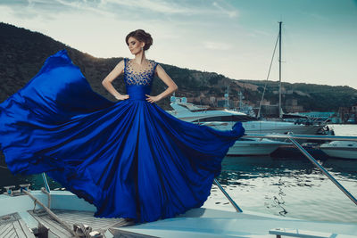 Portrait of woman with umbrella on boat against blue sky