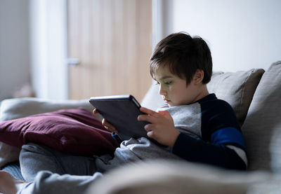 Boy using mobile phone on bed at home