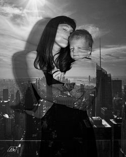 Double exposure of loving mother and son with cityscape