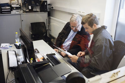 High angle view of owner discussing with client seen through glass at office