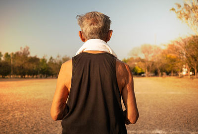 Rear view of man standing on field against sky
