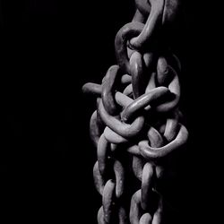 Close-up of rusty metal chains against black background