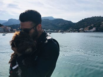 Man holding dog standing against sea