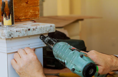 Cropped hand using nail gun on column