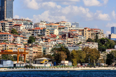 Buildings by river against sky in city