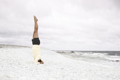 Man doing handstand on sandy beach