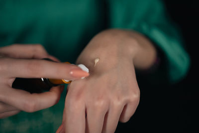 Midsection of woman holding hands against black background