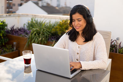 Young woman using phone while sitting on table