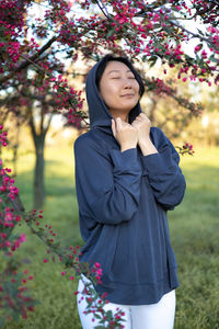 Portrait of young woman standing against trees