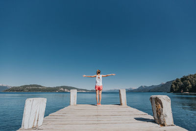 Man standing on lake against clear blue sky