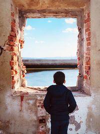 Rear view of man looking at sea against sky