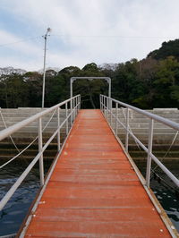 Footbridge over trees against sky