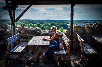 Side view of woman looking at forest while sitting at restaurant