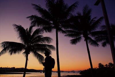 Silhouette palm trees at beach against sky during sunset