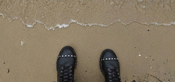 Low section of person standing on wet sand