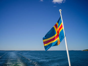 Flag flags on sea against clear blue sky