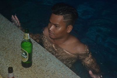 Portrait of young man eating food in swimming pool