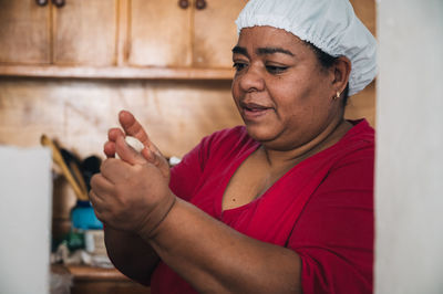 Venezuelan female preparing arepas at table with bowl at home