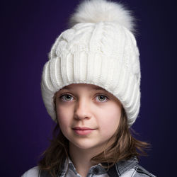 Portrait of smiling girl wearing knit hat against purple background