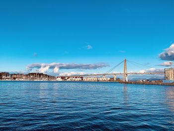 Bridge over calm river with buildings in background