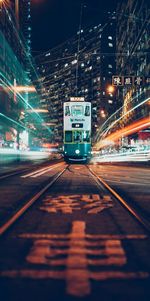 Illuminated railroad tracks in city at night