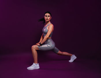 Portrait of young woman exercising against black background