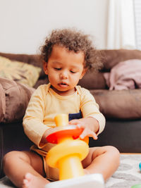 Cute mixed race or biracial baby boy playing with learning toys in the living room at home 