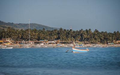 Sailboats moored in sea against sky