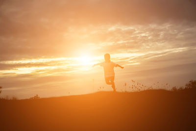 Full length of silhouette man standing on land against sky during sunset