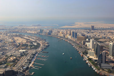 High angle view of city by river against sky